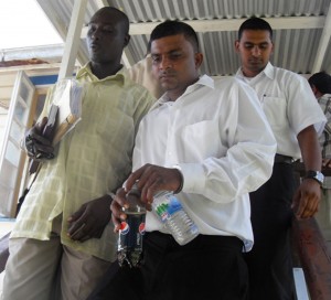 Murder accused Dwarka Gangadin  being led by detectives from the  Cove and John Magistrate’s Court 