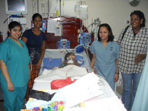 Udesh Ragubar is flanked by his mother (second from left), grandmother Basmattie Thomas (at right) and members of the overseas medical team one day after his operation at CHI.