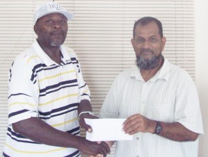 Managing Director of Mohamed’s Enterprise, Nazar Mohamed (right), hands over the sponsorship cheque to a grateful coordinator of the Futsal tournament, O’Neil Durant.  