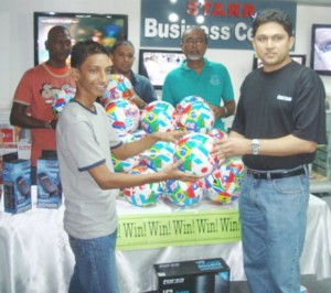 General Manager (STARR Computer Inc), Rehman Majeed hands over one of the balls to Ricaldo Purnwasy at the company’s headquarters. 