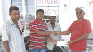 Sammy Rajpaul,  Trevor Balram and Parmanand Singh of the Rommel Jagroop Construction and Business Establishment at left presents the cheque to Dharmin Dharamjit of the Jumbo Jet racing establishment at the Entity’s Gas station and headquarters, Bush Lot West Coast Berbice.