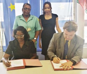 Ambassador Robert Kopecký and Ms. Omattie Madray sign the  grant contract while Chantalle Haynes, [standing right] Director of  Forward Guyana and Ann Greene of the Child Protection Agency,  Ministry of Human Services look on.