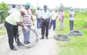 GPL operatives, in the company of police, rolling up some  of the illegal seized wires found in nearby premises.