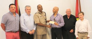 Mr. Dean Hassan presents the cheque to the Commissioner (Ag) while other company investors look on.