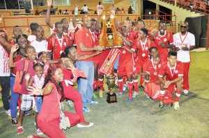 Digicel CEO Gregory Dean hands over the winning trophy and cheque to Christainburg/Wismar Secondary School Captain Jashawn Moore in the presence of teammates last night at the National Stadium. 