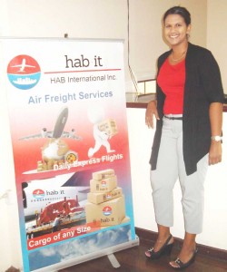 HAB’s Miami Manager, Ms. Tina Beharry stands next to a company poster.