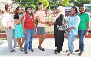 MHA Emancipation Queen Dominoes  winner Ms. Teshina Marcus  receiving her trophy from Mrs. Mohammad in the  presence of other participants.