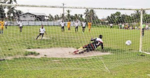 Agricola Red Triangle’s Gordon Grant scores from the penalty spot against Javier Greene.