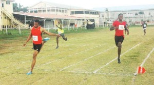 Elton Bollers (left) whisks past the finish line in the ‘final-by-time’ 200m yesterday at the Police Sports Club Ground, Eve Leary.