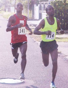 Cleveland Thomas (right) makes his move from Kelvin Johnson yesterday morning on Lamaha Street in the Courts 10km Road Race. 