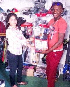 Trevon Griffith collects his batting gloves from Universal Sports staff member Natalie Ramkarran  at the Store’s 2nd Street Alberttown location.