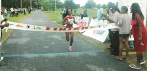 Trinidad and Tobago’s Tonya Nero bursts through the finish line tape unchallenged yesterday in the IAAF South American 10km Road Race.