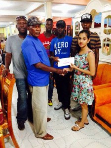A representative of the Home Line Furnishing Store presents the sponsorship cheque to coordinator and Coach Randolph Roberts. 