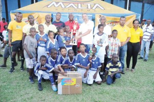 Courts Managing Director Mr. Clyde De Hass presents the winning trophy to Stella Maris Captain Darron Niles in the presence of his teammates and other tournament officials. Banks DIH’s Clayton McLeod (centre) also shares the moment.     