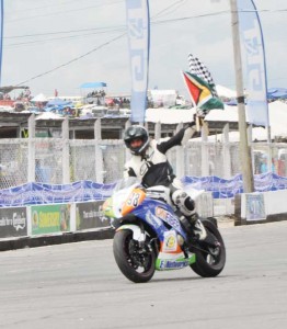 Superbike king Nikhil Seereeram waves the chequered and national flags after capturing one of the two races he won yesterday.