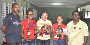 The Athletes with their trophies and kits standing from left, Valesa Harding, Mary Leandrew and Simona Lawrence. Former chairman of the Region nine Athletics club Sugreem Singh is at far right, while present chairman Kenrick Lewis is at extreme left. 