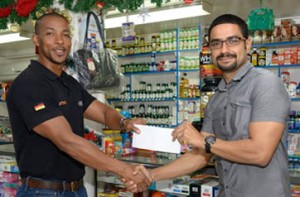 Managing Director of Medicare, Christopher Lowe (right) hands over the cheque at their Sandy Babb Street location to Onai Vasconcellos, Flex Night Inc. Director of Advertising.