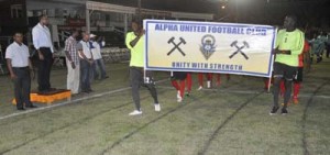Minister of Sport Dr. Frank Anthony (centre), GFA president Vernon Burnette (left), Banks Beer Brand manager Jeoff Clement (second from right) and Brain Choo-hen take the March Past as Alpha United FC display their banner.