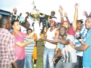 Banks DIH Limited Supervisor Nandram Basdeo presents the winning trophy in the feature event to a Rep of the Elcock Stable for Curfew Tower’s victory. Jockey Junior Sookhan sits astride the horse.