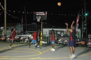 LIGHTS OUT! Geoffrey LaRose (right) releases one of many missiles from downtown Sunday night at the Independence Boulevard Court in Albouystown in the opening of the Mackeson 3x3 ‘King of Rim’ Basketball Challenge. 