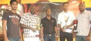 Mackeson Brand Manager, Jamaal Douglas (centre) takes a photo  moment with representatives from the winning team, Pitbulls  and runner-up, Pacesetters ‘A’ yesterday following the  presentation of their prizes at the Ansa Mcal headquarters. 