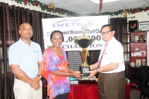 Chief Executive Officer of Metro Avia Maria Lindie (left) presents the trophy to KMTC president Cecil Kennard, while Manager Bernard Ramsaroop looks on.  