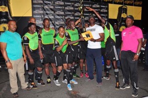 Guinness Brand Manager Lee Baptiste hands over the winning trophy and first prize money to North Ruimveldt Captain in the presence of teammates and Petra Organisation Co-Director Troy Mendonca during the presentation ceremony.