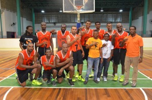 Ravens’ Coach, Darcel Harris (right) joins his team with the show of the sign ‘three’ signaling their third straight Phillip George Legacy tournament title at the Cliff Anderson Sports Hall on Saturday night.