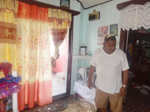 An injured Chandradeo Ramlakhan standing next to the broken door 