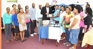Southern Systems CEO Karl Moore (centre) hands over one of the tablet computers to  Deputy Head of the Library, Nadine Moore, in the presence of other library staffers.