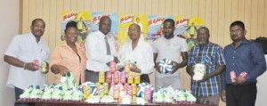 Company secretary Percival Boyce (right) presents a pair of booths to President of Sunburst Campton FC James Bond while officials of the entity and club share the moment. 