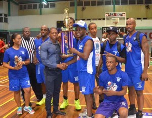 Guyana’s bodybuilding king, Kerwin Clarke hands over the Championship Trophy to captain of Team Bond, James Bond Saturday night in the Respect the Game Charity Basketball Event.