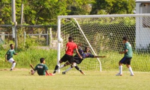 Three Queenstown Sec players converge on a loose ball as a lone defender tries to protect his Goalkeeper Colin Bacchus from further torture.