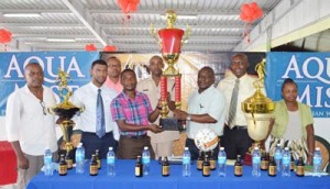 Banks DIH Communications Manager, Troy Peters (third right), presents the championship trophy to WDFA President, Nigel Garraway. Other officials of Banks DIH Limited and the WDFA share the moment. 