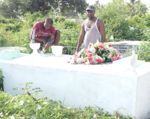 Colin Tull (right) took time out to remember his wife Lovina by painting her tomb yesterday.