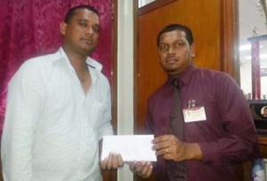 Inshan Satar (right) of Jim Bacchus Travel Service hands over sponsorship cheque to Arshad Rahaman, a representative of the YWCC.