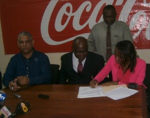 Genevieve Blackman (extreme R), affixes her signature to the document in the presence of Olato Sam (2nd R), Carlton Joao (extreme L) and Troy Peters (standing).