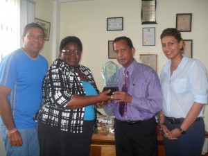 Ms. McCalman presenting a plaque to Mr. Panday. Looking on approvingly are Mr. John Goede, ITF Development Officer for the Caribbean and Ms. Elizabeth Persaud, Treasurer of the Guyana lawn Tennis Association.