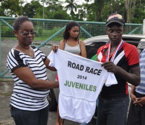 GCF President Ms. Cheryl Thompson presenting inaugural Juvenile Raod race champion Andrew Hicks of Berbice with his jersey.   