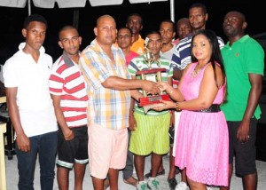 Managing Director of August Beverage Enterprise, Shellon August (right) presents the winning trophy and cash prize to captain of the victorious Spartons team, Navin Singh in the presence of his teammates and other members of the sponsor. 