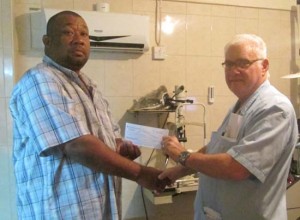 Dr. Jose Da Silva of Modern Optical Services hands over cheque to Secretary/CEO Hilbert Foster of the RHTYSC   
