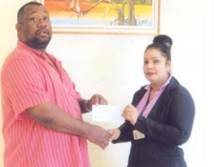 Ms. Bibi Ali hands over the cheque to Hilbert Foster. 