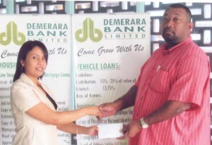 Ms Earlene Dawson, Demerara Bank, Rose Hall Town Manager hands over cheque to Secretary/CEO Hilbert Foster.