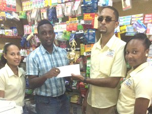 Jose Emerson (2nd right), Manager of Rubigee’s Pharmacy hands over the fourth place trophy and an undisclosed sum of cash to Aubrey Major Jr. in Linden.