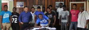 Jason St Clair signs his contract at the GCB office yesterday as the other players and CGI Chairman Raj Singh witness the signing. 