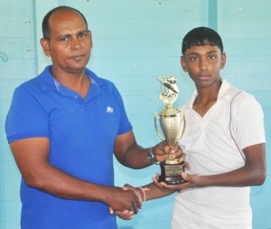Man of the Match Kelvin Omroa (right) collects his trophy from chairman of GCB junior selection panel Nazimul Drepaul.