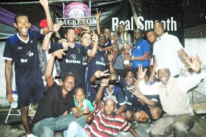 NEE’s Shareef Major, Winston Fraser and Aubrey Major Jr, (standing, right) present the winning trophy to a celebrating Show Stoppers squad Saturday night in Linden.