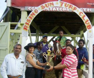 Owner of Mary Ann of the champion Lenny Singh stable (right) receives the  I3 trophy  from Mrs Ouditt. 