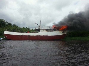 Fire rages from the bow of the trawler.