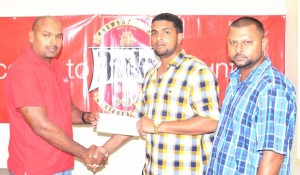 Banks DIH’s Mr. Gavin Jodhan (left) presents the cheque to Coordinator Nazrudeen ‘Jumbo Jet’ Mohammed Jr at their Thirst Park Head Office. 